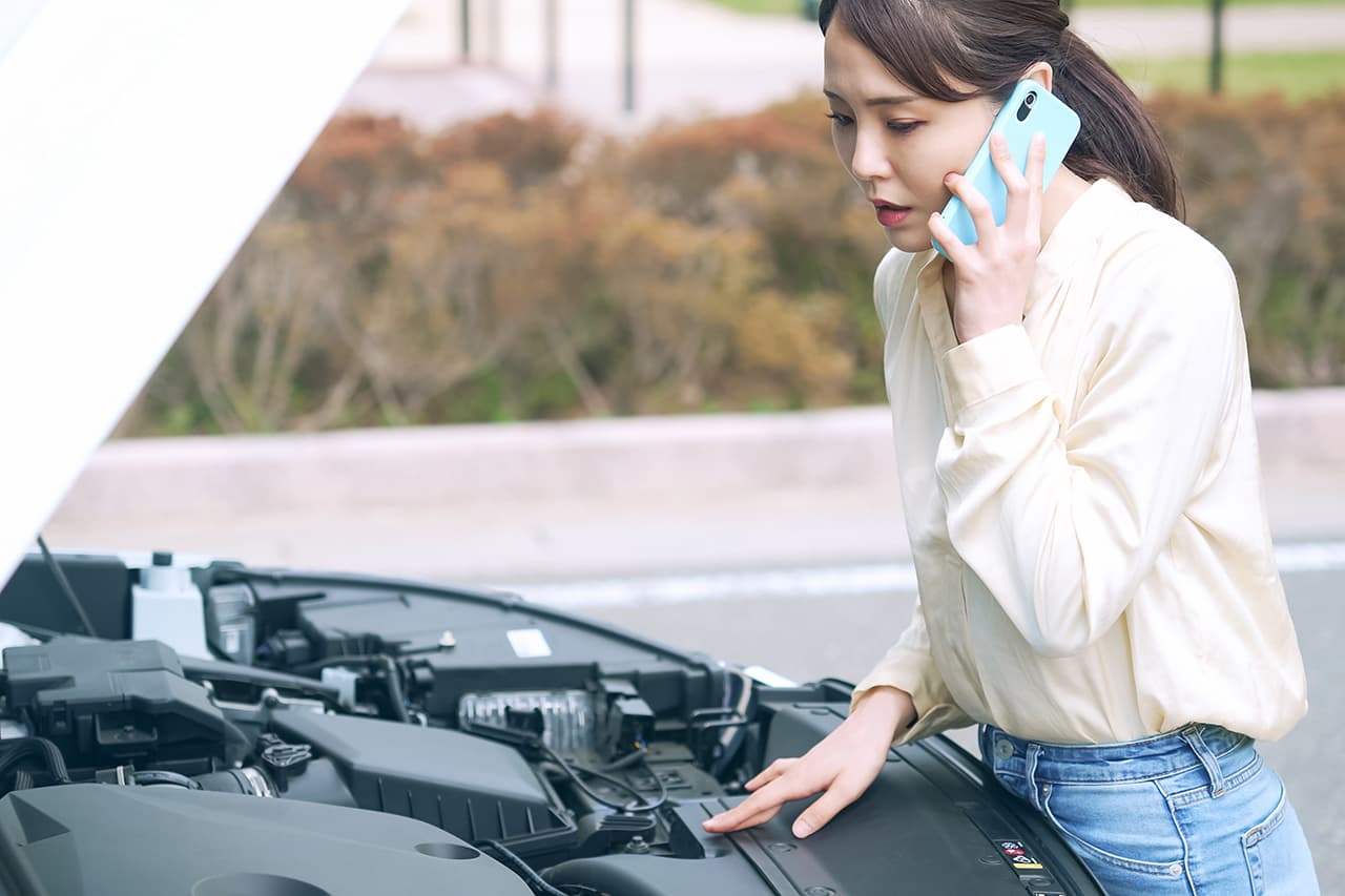 車のトラブルで電話をかける女性